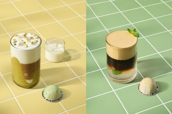 Dwa letnie napoje przygotowane z kawy Nespresso – po lewej warstwowy napój z mlekiem, pianką i pistacjami na żółtych kafelkach, po prawej chłodna kawa z miętą i pianką na zielonych kafelkach, obok każdej z nich kapsułka Nespresso.
